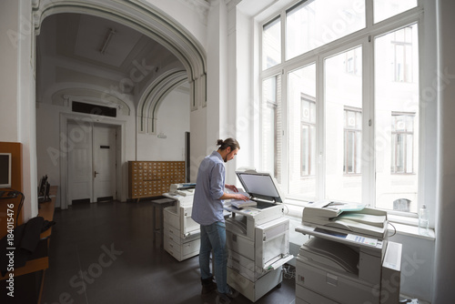 Male student using copymachine in public library photo