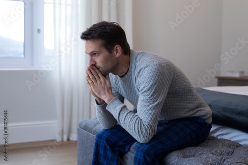 Thoughtful man sitting on bed