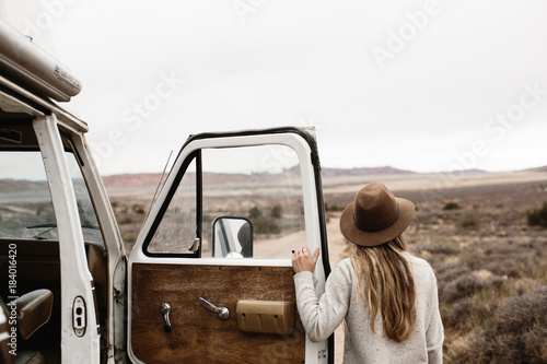 woman with hat looking out into landscape from van door photo