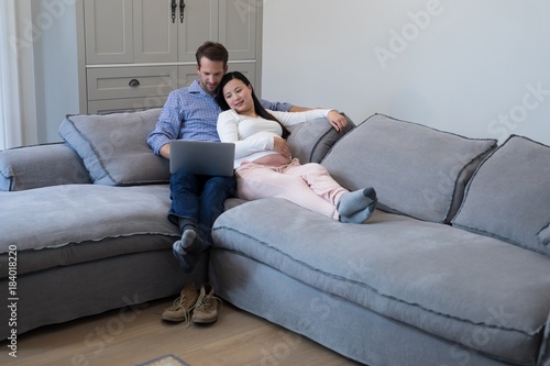 Couple using laptop on sofa