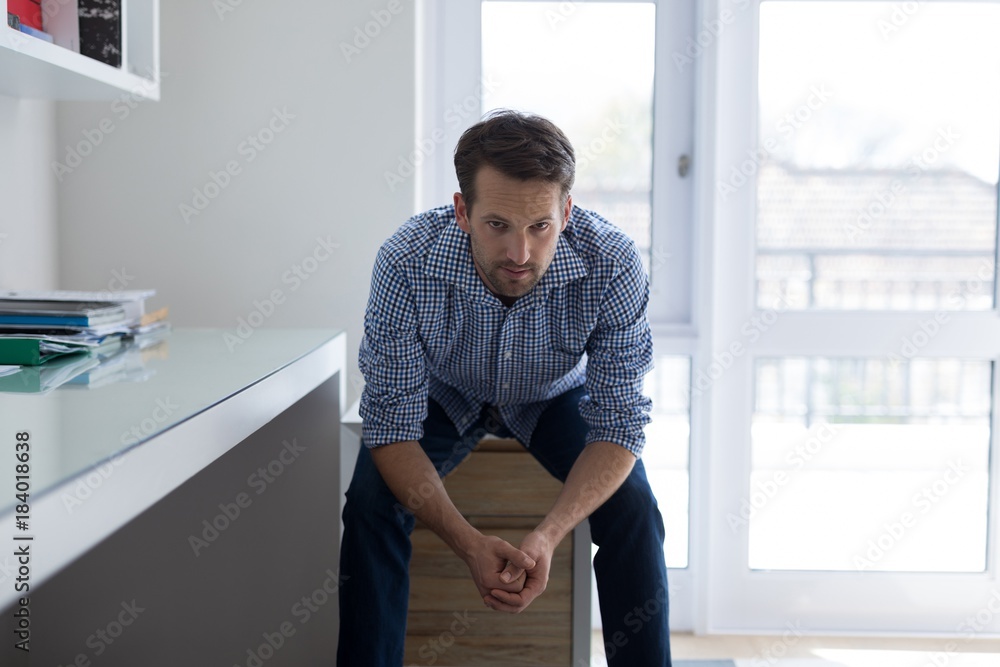 Portrait of confident man sitting on drawer Portrait of confident man sitting on drawer