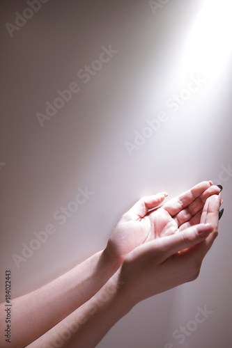 Hands under the glowing light ready to recieve Grace of God. Fervent prayer concept