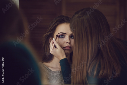 Make-up artist doing makeup to girl in studio.