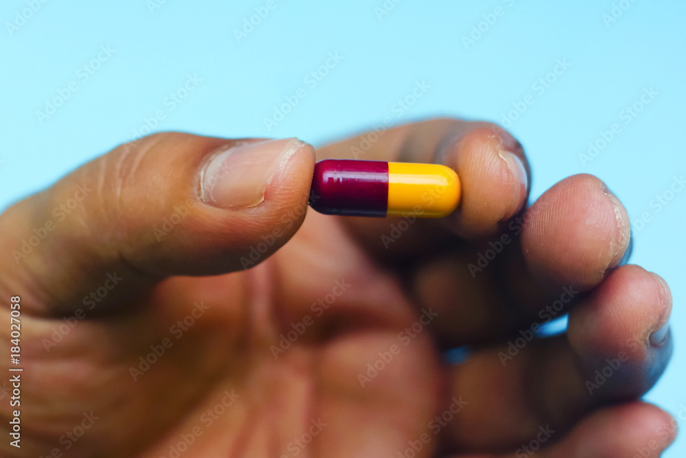 Hand Holding Capsule Over Blue Background Hand Holding Capsule Over Blue Background