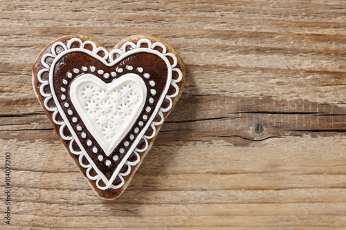 Gingerbread cookie in heart shape on wood