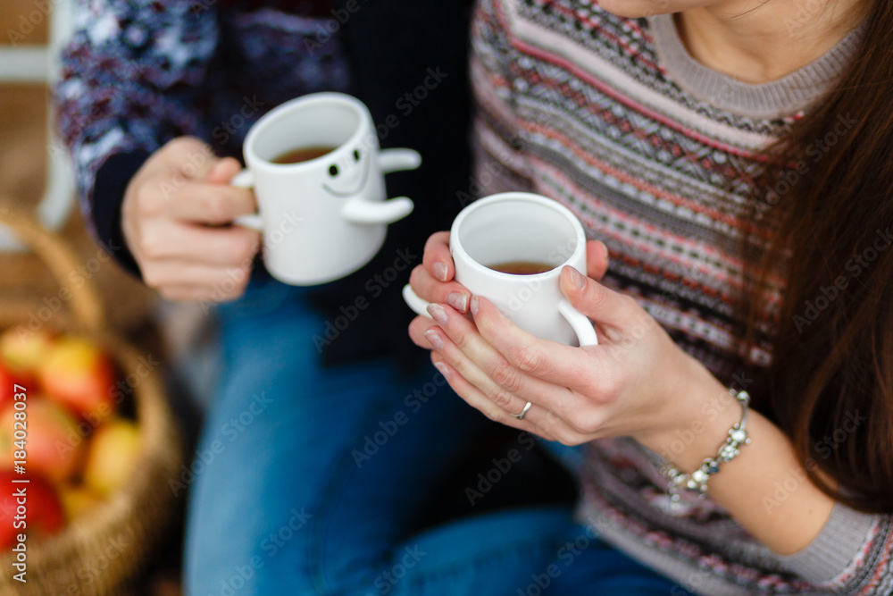 Hands close up of Couple drinking a hot drink from cups at picnic sitting on a blanket. Boy and Girl in love sitting on a picnic plaid in a park, drinking coffee and enjoying their day out in nature Hands close up of Couple drinking a hot drink from cups at picnic sitting on a blanket. Boy and Girl in love sitting on a picnic plaid in a park, drinking coffee and enjoying their day out in nature