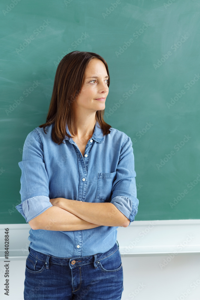 lehrerin steht mit verschränkten armen vor der tafel und schaut zur seite