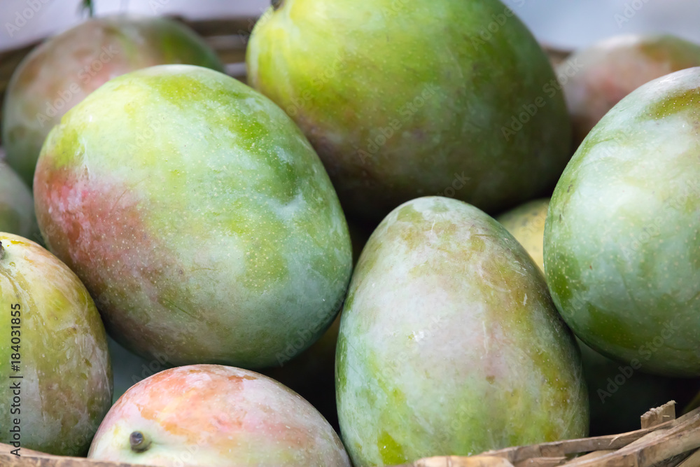 Green tasty mango with red-yellow tint of color in the basket Green tasty mango with red-yellow tint of color in the basket
