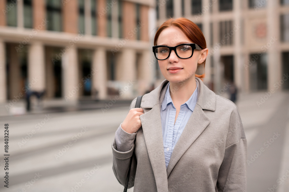 Young manager in eyeglasses looking at camera in urban environment while going to work Young manager in eyeglasses looking at camera in urban environment while going to work