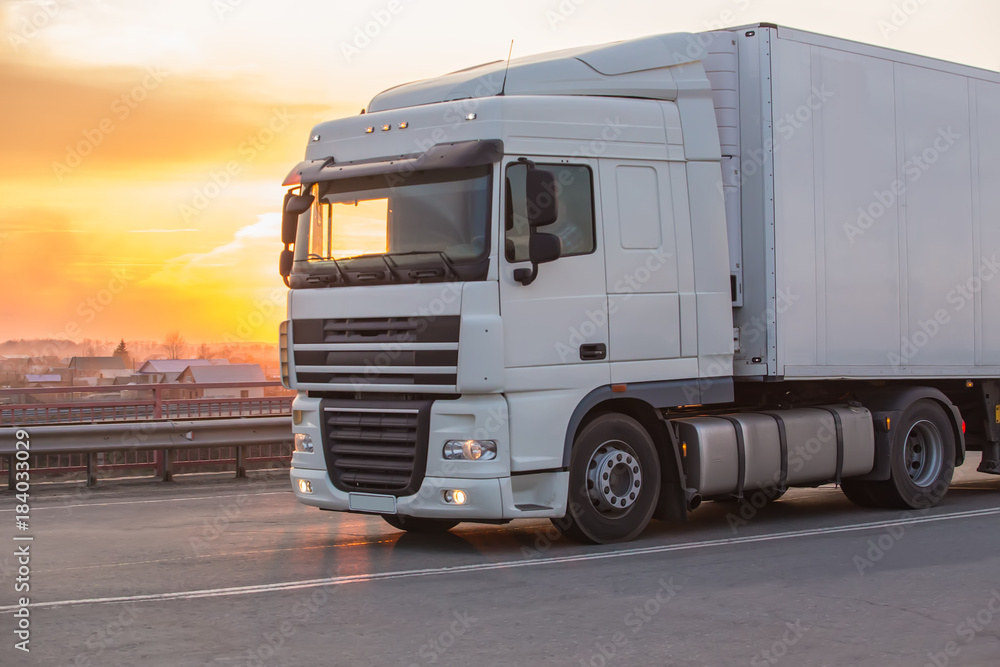 Naklejka premium truck goes on highway on sunset