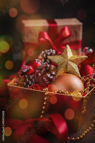 Composition with gift and Christmas decorations in golden box on black background toned bokeh