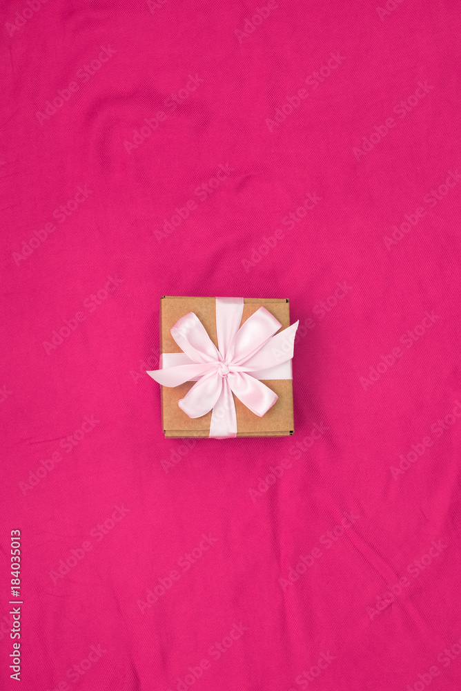 One gift box tied with satin coloured ribbon on a red background One gift box tied with satin coloured ribbon on a red background