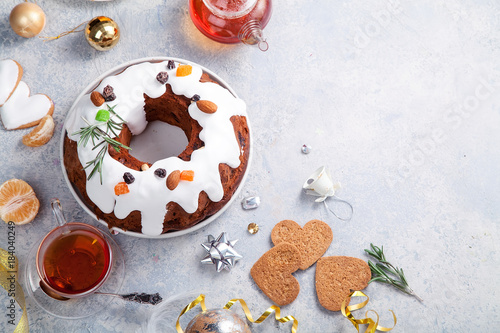 Traditional christmas cake with dried fruits soaked in rum and sugar glaze. Teatime with heart-shaped ginger cookies. Christmas background with festive decoration. Copy space.