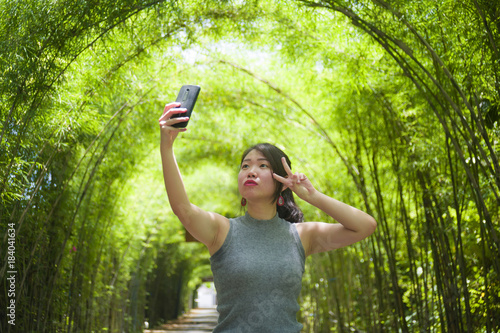 young pretty Chinese Asian woman enjoying having fun taking selfie picture with mobile phone camera posing cool