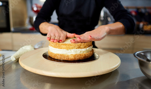 Hands of a confectioner's woman with cake crusts on a table in the kitchen.