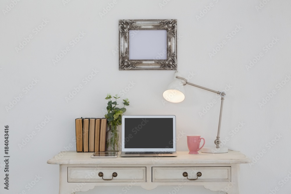 Electronic gadgets, lamp, book, mug, flora and book on table Electronic gadgets, lamp, book, mug, flora and book on table
