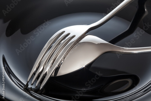 Empty plate with spoon and fork on a black background