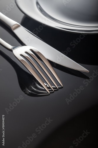 Empty plate with knife and fork on a black background