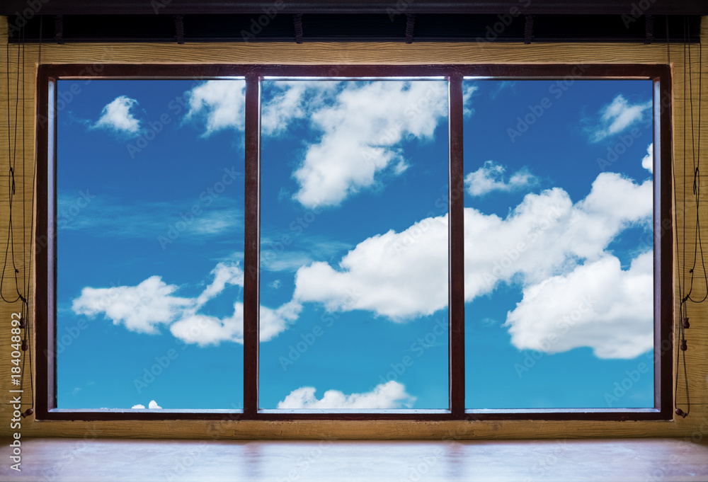Fototapeta premium Looking through window, wooden window frames with blue sky and white clouds view