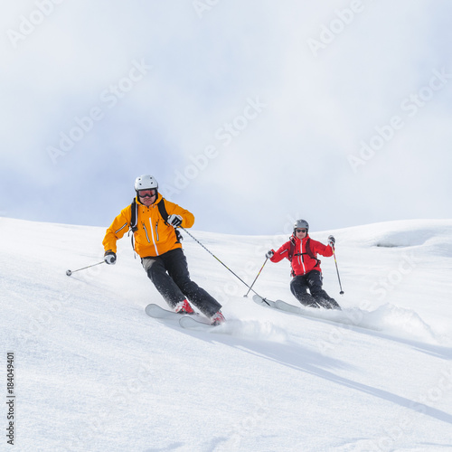 Zwei Skifahrer befahren gemeinsam einen steilen Hang