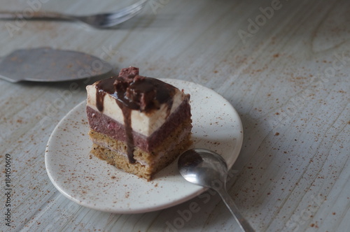 Gentle Muscovy cake with raspberry curd and poppy cakes, decorated with strawberries, chocolate, marshmallows and frosting on a light wooden background