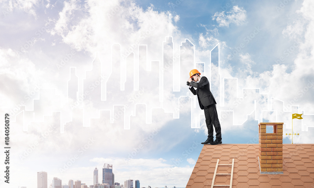 Engineer man standing on roof and looking in binoculars. Mixed media Engineer man standing on roof and looking in binoculars. Mixed media