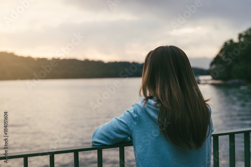 Lonely woman standing absent minded at the river photo