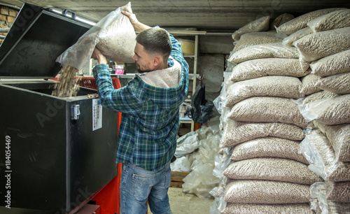 the man loads the pellets in the solid fuel boiler, economical heating