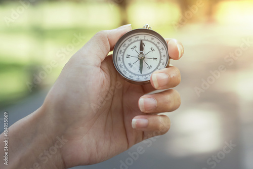 Compass in the hand with background of green nature.