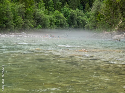 group of kayakers in the mist at the river soca, slovenia