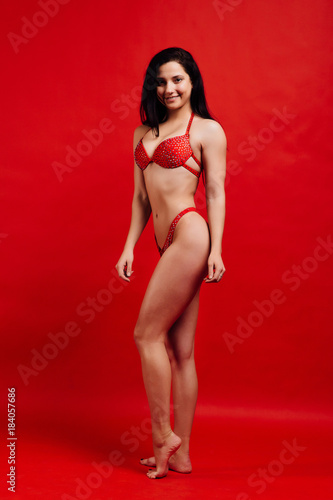 beautiful young girl fitness model stands on red background in sexy bra. © photominus21