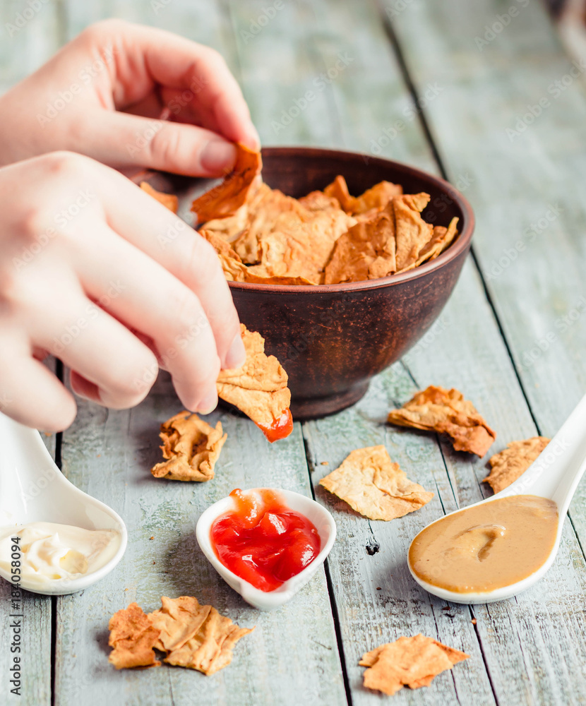 Healthy chips a tortilla, nachos with a organic classic sauce - ketchup, soy mayonnaise and mustard. Eating hand. Healthy chips a tortilla, nachos with a organic classic sauce - ketchup, soy mayonnaise and mustard. Eating hand.