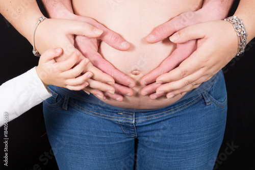 hands of the whole family on the belly of the pregnant woman