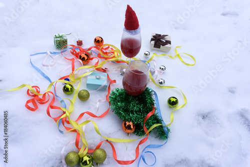 Two glasses with red wine on wooden table with fairylights and merry christmas card