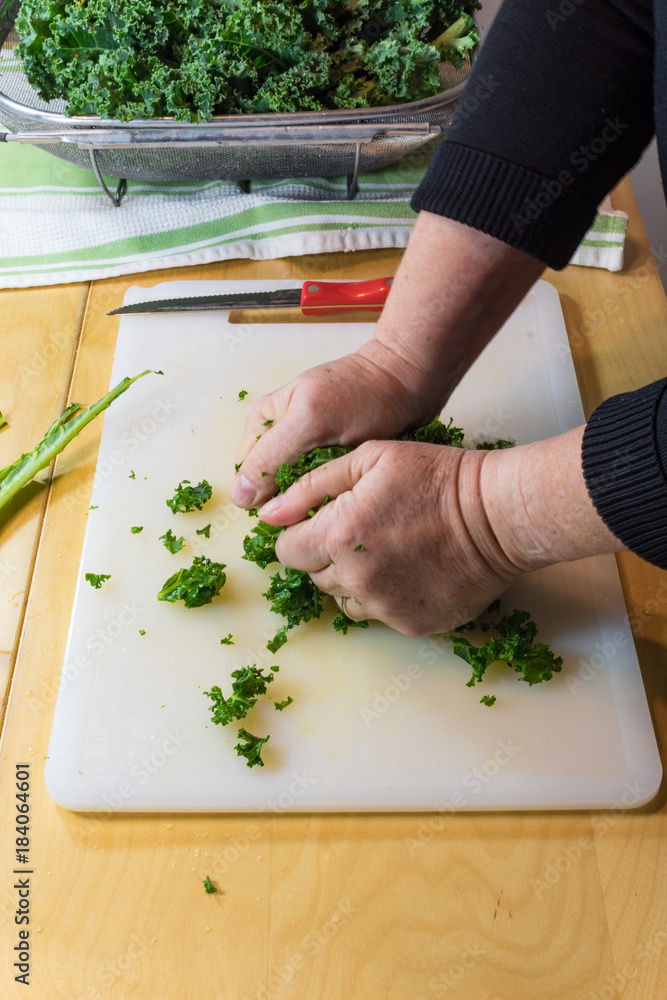 Hands of a woman crushing and massaging kale leaves to break down the tough fibers, vertical aspect Hands of a woman crushing and massaging kale leaves to break down the tough fibers, vertical aspect