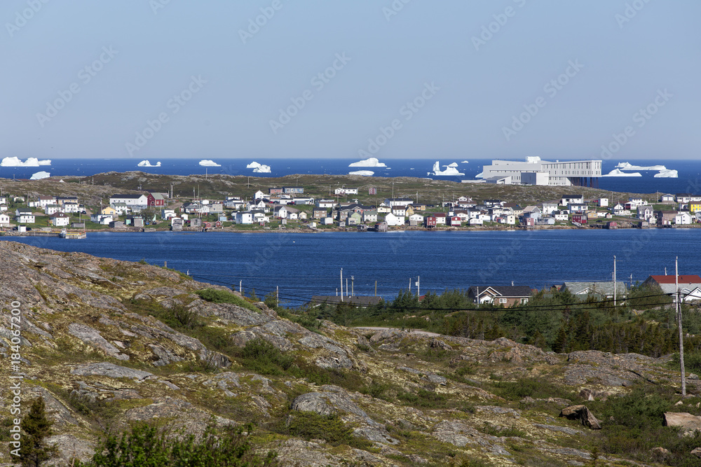Newfoundland coastal town with modern hotel and icebergs