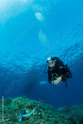 woman scuba diving over rocks in the Mediterranean Sea © Subphoto