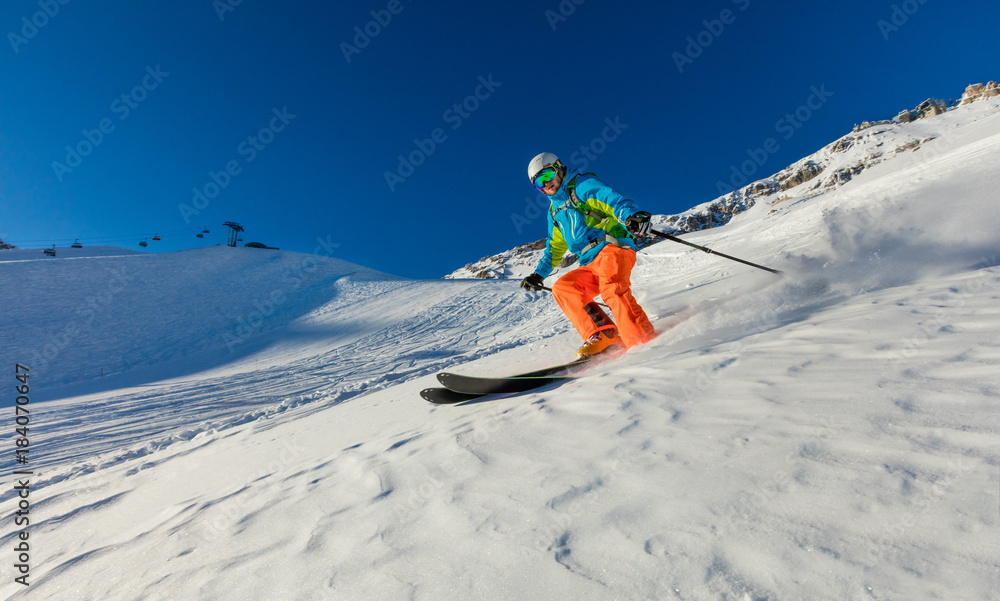 Young skier running downhill in beautiful Alpine landscape.