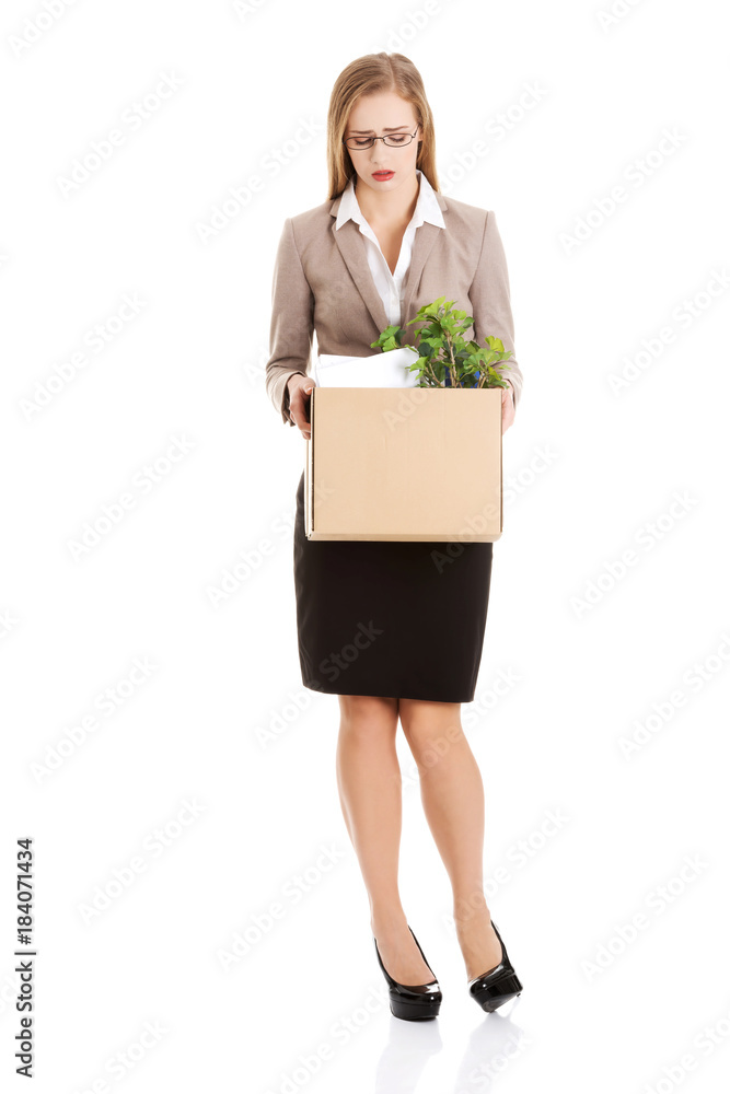 Beautiful caucasian business woman is sad because she was fired from work and is holding box with her personal things. Beautiful caucasian business woman is sad because she was fired from work and is holding box with her personal things.