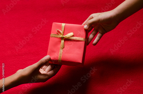 Closeup of Hands holding Gift box on Red Background. Happy New year and Christmas Concept.