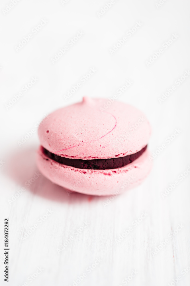 Making homemade French Macarons with raspberry coffee flavor: Close up of imperfect, light pink macarons filled with chocolate ganache on white wooden background Making homemade French Macarons with raspberry coffee flavor: Close up of imperfect, light pink macarons filled with chocolate ganache on white wooden background
