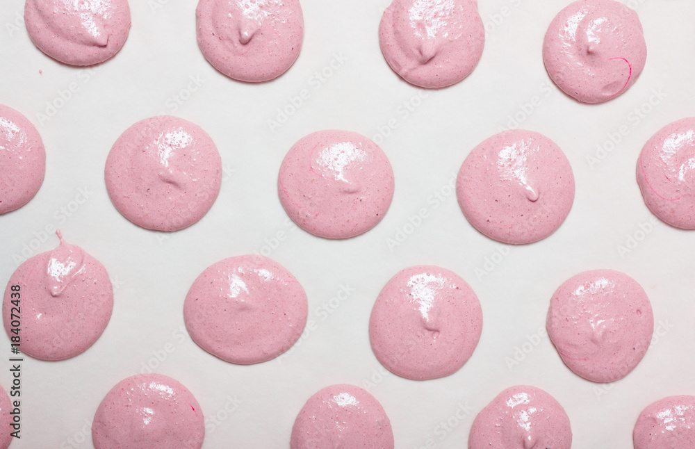 Making homemade French Macarons with raspberry coffee flavor: light pink,  unbaked macaron batter, so called macaronage, piped in circles on white parchment  paper before baking Stock Photo