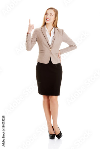 Beautiful caucasian business woman is pointing up.