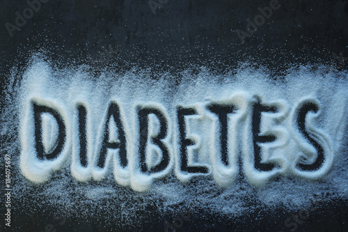 The word diabetes written into a pile of white granulated sugar with a black background.