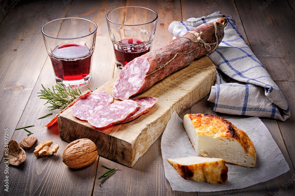 Salami, cheese and red wine on wood background