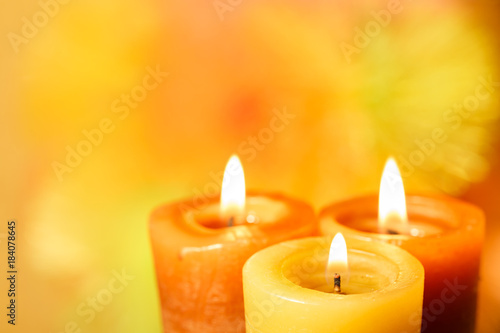 Three burning candles on a bright blurred background closeup