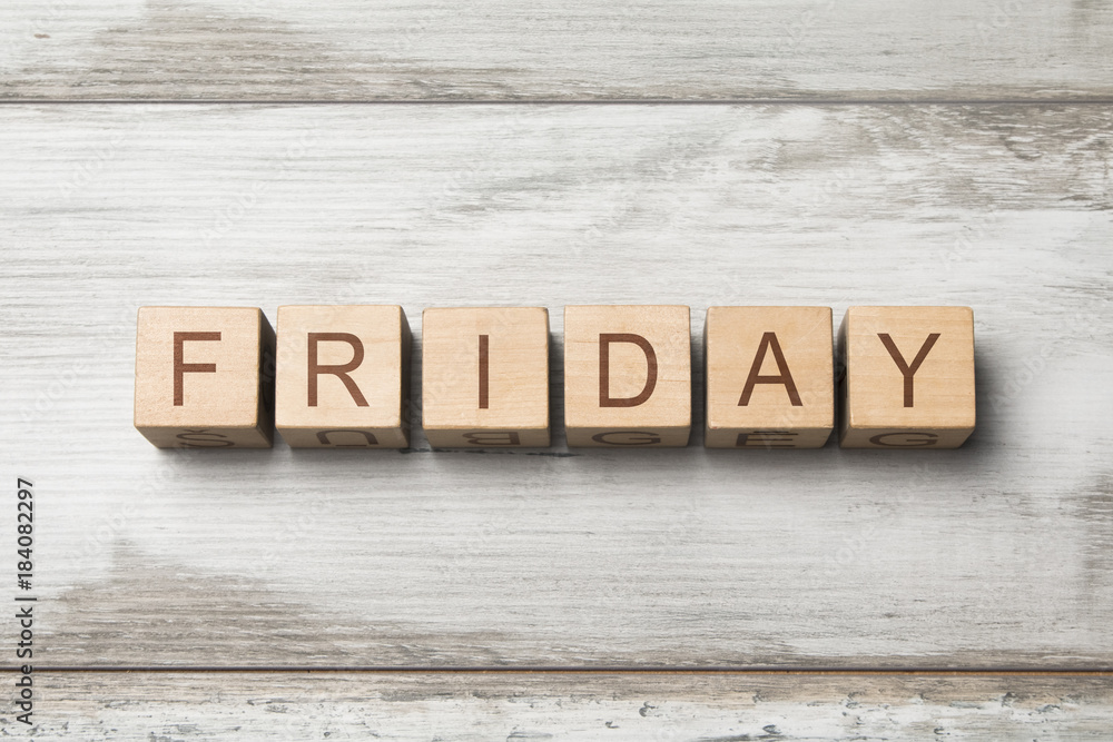 Fototapeta premium FRIDAY word written on wooden cubes on wooden background