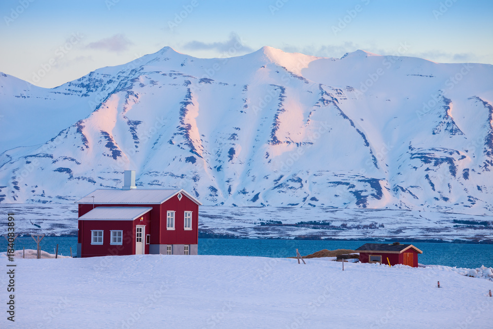 Fototapeta premium Iceland winter landscape with solitary living house positioned of the fjord at dawn (near Akureyri), northern Iceland.