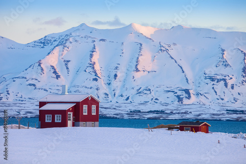 Iceland winter landscape with solitary living house positioned of the fjord at dawn (near Akureyri), northern Iceland.