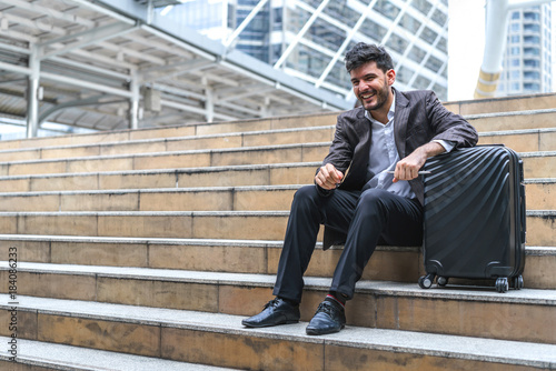 Business man sitting on stair with luggage in the routine of working with determination and confidence. concept of business trip travel and transportation. © bixpicture